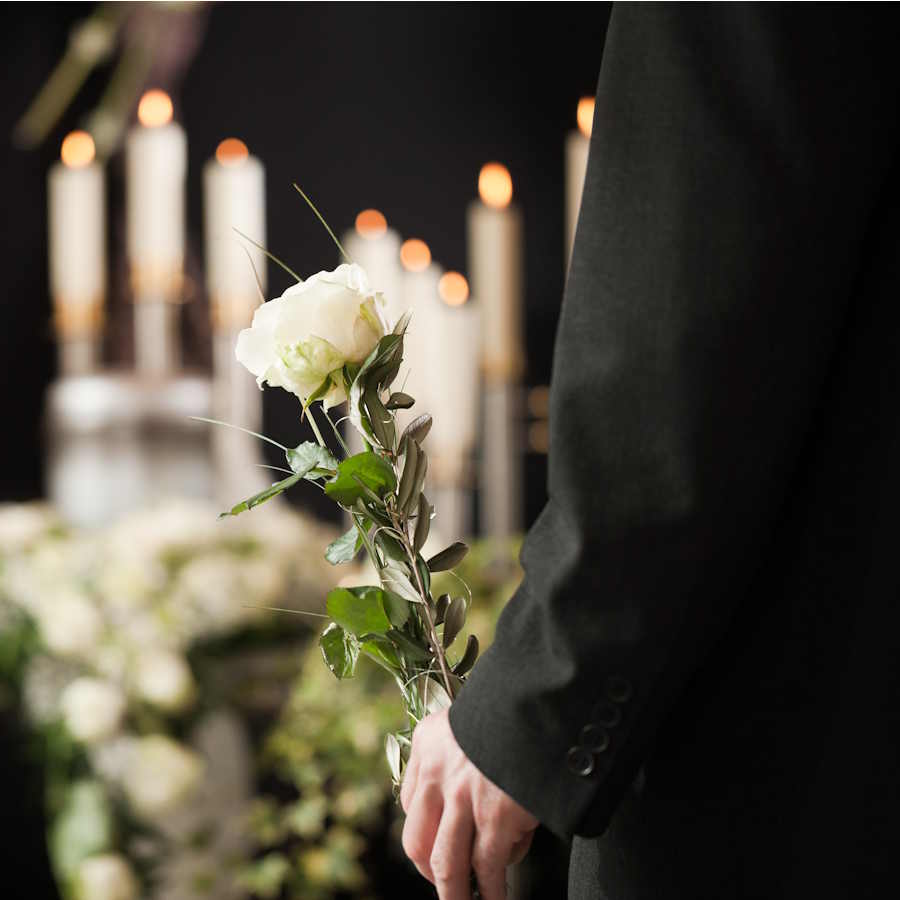 Mann mit weißer Rose vor Kerzen und Blumenschmuck – symbolischer Abschied bei Bestattungen in Lägerdorf und Umgebung